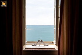   At Castello di Duino, Duino, Trieste, Italy, the bride’s delicate shoes rest gracefully on a windowsill, their placement offering a stunning view overlooking the sparkling sea.